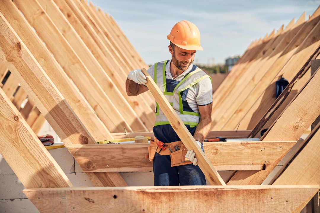 focused builder is adjusting a wooden bar to a roof carcass.jpg